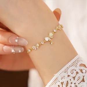 Detail view of 18K gold-plated zircon bowknot star charm bracelet on a woman's wrist