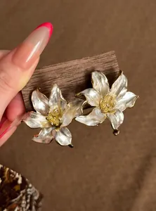 Primer plano de elegantes pendientes de flor blanca sobre soporte de madera