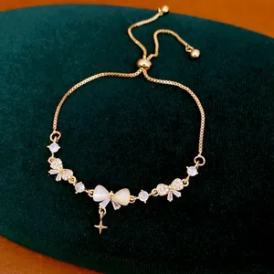 Detailed view of 18K gold plated bow and star charm bracelet on green velvet