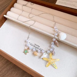 Close-up of a pearl necklace with starfish and shell pendants in a jewelry tray