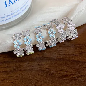 Primo piano di eleganti orecchini a fiore a forma di C con zirconi e dettagli in smalto