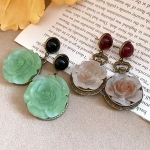 Macro detail of vintage-style resin rose flower drop earrings featuring an antique metal finish