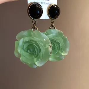 Detail shot of vintage style green resin rose flower drop earrings with black studs