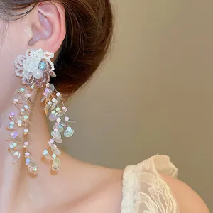 Detail view of dainty white floral tassel earrings with iridescent sequin dangles.