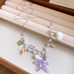 Close-up detail of summer starfish shell necklace with pearls and purple glitter pendant