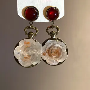 Detailed view of vintage silver needle resin rose pendant earrings with red cabochon studs.