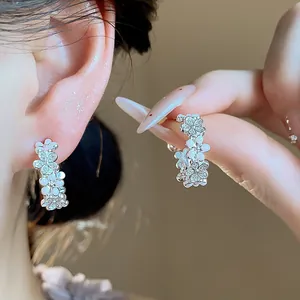Dettaglio di orecchini a lobo a forma di C in argento con fiori di zirconi e smalto
