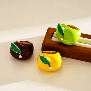 Close-up of vibrant enamel apple-shaped rings arranged on a wooden jewelry display