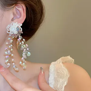 Close-up detail of stylish sweet floral tassel earrings with colorful sequins on ear.