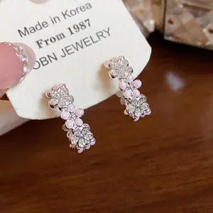 Dettaglio ravvicinato di orecchini a C con fiori rosa, zirconi e finitura in argento