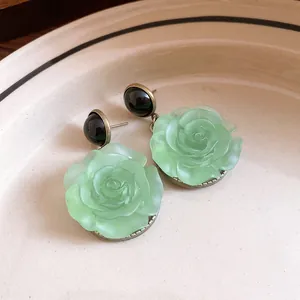 Detailed macro view of elegant vintage resin rose earrings with light green petals