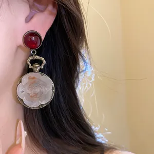 Detail shot of vintage resin rose drop earrings with red stud on an Asian model's ear