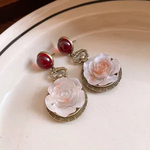 Detailed macro view of vintage resin rose earrings with elegant red bead accents