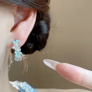 Eleganti orecchini a fiore in argento con smalto blu e zirconi, dettaglio raffinato.