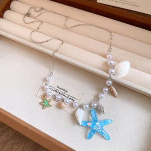 Detailed view of handmade pearl necklace featuring blue starfish and white shell charms