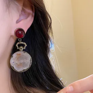 Close-up of retro resin rose drop earring worn on ear with elegant red stud.
