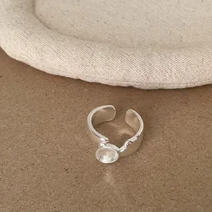 Nahaufnahme eines minimalistischen silbernen offenen Rings mit rundem Stein