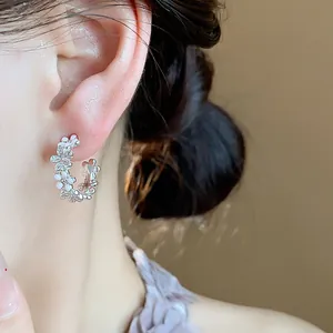 Primo piano di eleganti orecchini a lobo a forma di C color argento con fiori e zirconi