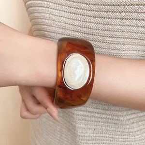 Close-up of retro Maillard brown resin bangle with pearlescent oval inlay detail.