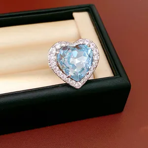 Detailed close-up of heart-shaped ring with light blue zircon and surrounding halo stones