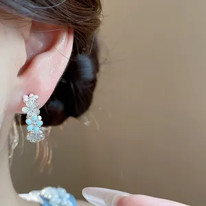 Dettaglio di orecchini a fiore a forma di C con smalto blu e rosa e zircone