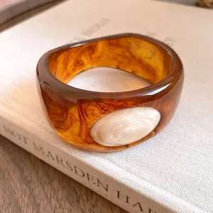 Close-up of retro amber resin bangle with marbled texture and cream inlay detail