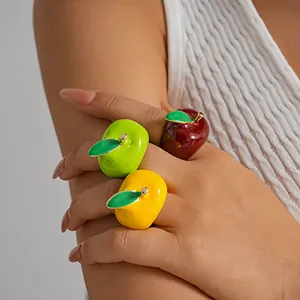 Close-up of three vibrant apple-shaped enamel rings in red, green and yellow
