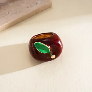 Detailed macro view of an elegant dark red apple ring with a vibrant green leaf detail