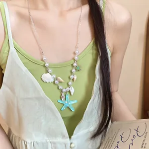 Detail shot of ocean-themed necklace with starfish, shells, and pearls on a model.