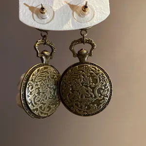 Detailed macro view of vintage bronze round earrings with intricate floral relief patterns.