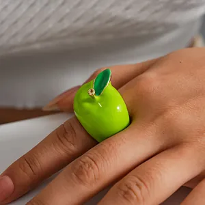 Detailed view of a creative green apple shaped dopamine enamel ring worn on a finger