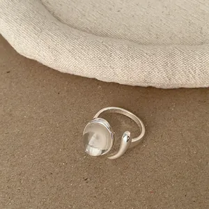 Detailansicht eines silbernen offenen Rings mit klarem ovalem Harzstein