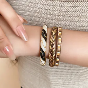 Close-up of three Maillard style stackable bracelets on a wrist with neutral sweater