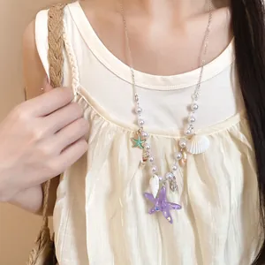Detail view of summer starfish and pearl shell necklace on model for beach vacation.