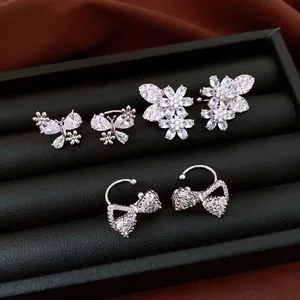Detailed macro shot of sparkling zircon ear cuffs with butterfly, flower and bow designs