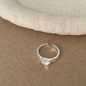 Detailaufnahme eines minimalistischen silbernen Rings mit rundem, durchscheinendem Stein