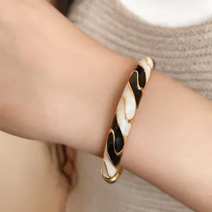Close-up of retro black and white drip oil buckle bangle shown on a woman's wrist