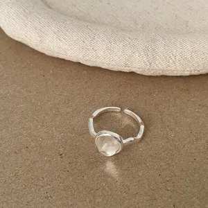 Detailansicht eines minimalistischen silbernen Rings mit rundem milchigen Edelsteinen.