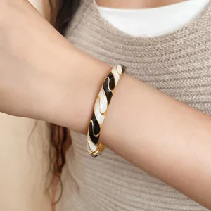 Detailed view of a retro gold buckle bangle with black and white enamel wavy patterns