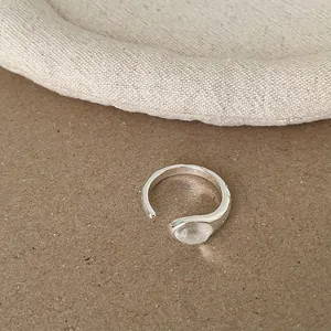 Detailaufnahme eines silbernen offenen Rings im minimalistischen Design mit Stein.