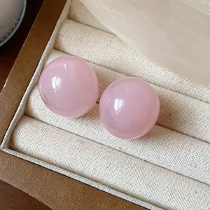 Detailed macro view of glossy pink resin spherical stud earrings in a velvet tray