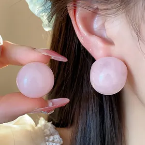 Macro detail view of a minimalist pink resin round stud earring worn on the ear