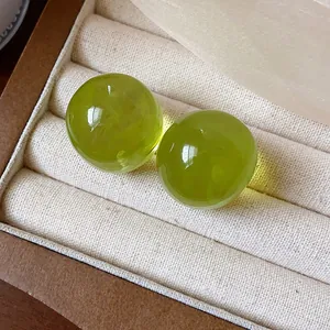 Close-up of minimalist lime green translucent resin round ball stud earrings