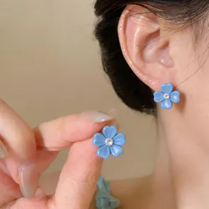 Detailed view of elegant blue flower stud earrings with sparkling zircon center on ear