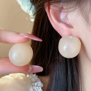 Detailed view of glossy cream resin round stud earrings showing material and large size