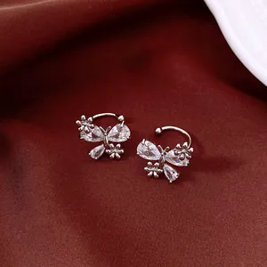 Detailed view of silver butterfly ear cuffs with sparkling cubic zirconia on red fabric.