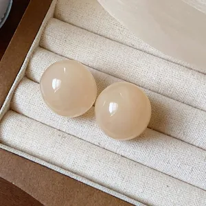 Detailed macro shot of smooth beige resin round stud earrings in a luxury jewelry box