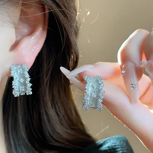 Close-up showing the elegant sparkle and texture of zircon-studded C-shaped silver earrings
