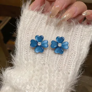 Close-up of blue cat eye stone flower earrings with zircon center on white sweater