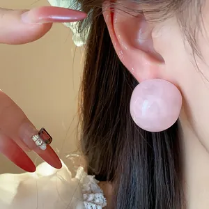 Close-up view of elegant pink round resin stud earring with marble texture on model